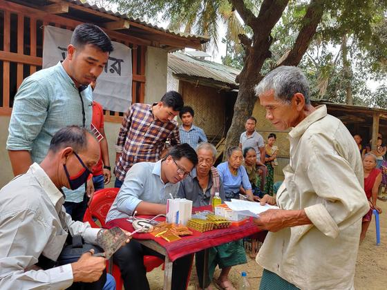An older man reading a prescription slip beside the consultation table