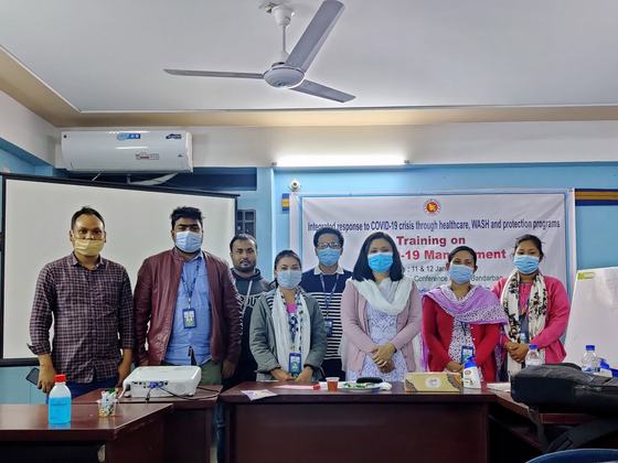 Facilitators and participants standing together in front of the training banner
