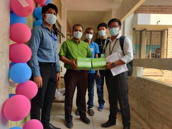 Five masked staff members holding boxes of medical oxygen regulators
