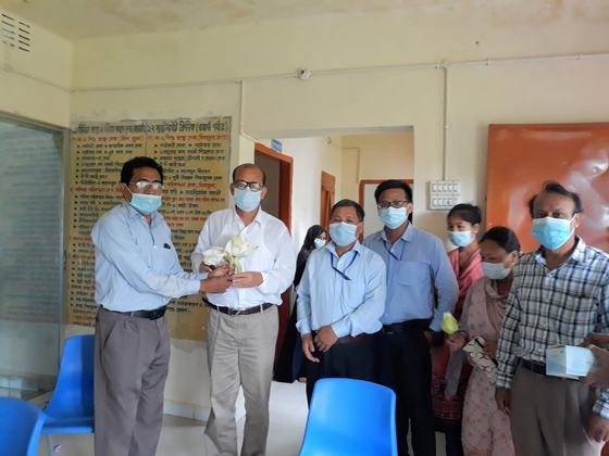 Masked health officials exchanging lotus flowers inside the family welfare centre